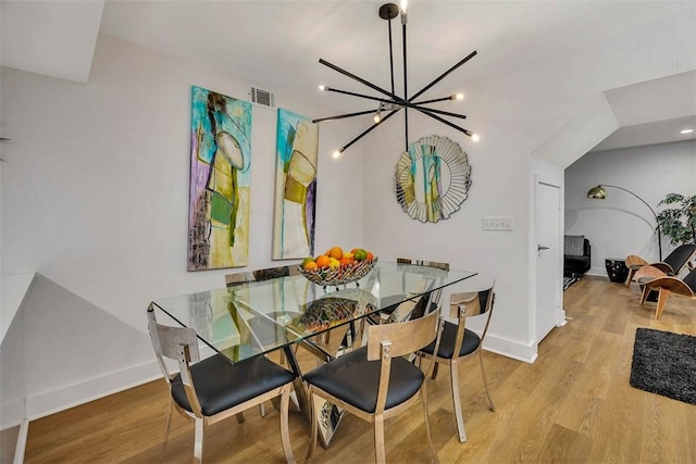 dining area with light hardwood / wood-style flooring and a notable chandelier