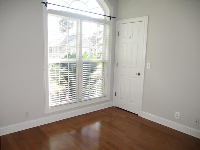 empty room with dark wood-type flooring and a healthy amount of sunlight