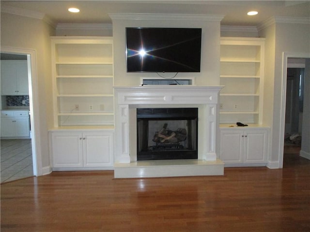 unfurnished living room with built in shelves, dark wood-type flooring, and ornamental molding