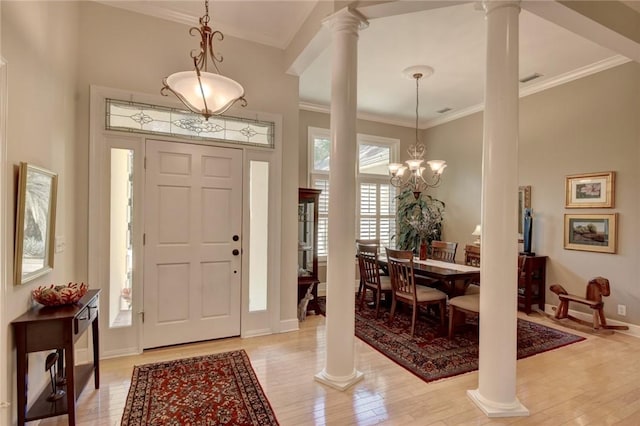 entrance foyer featuring a notable chandelier, light hardwood / wood-style floors, ornate columns, and ornamental molding