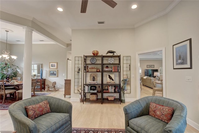 sitting room featuring decorative columns, ornamental molding, ceiling fan with notable chandelier, and hardwood / wood-style flooring