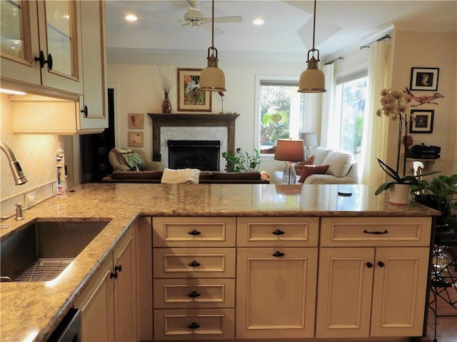 kitchen with light stone countertops, tasteful backsplash, ceiling fan, sink, and pendant lighting