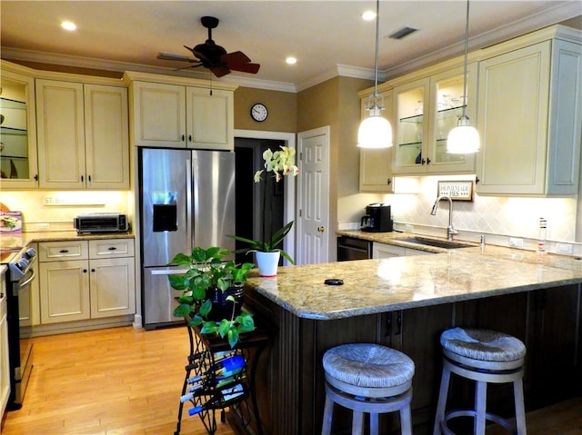 kitchen with a breakfast bar, sink, black appliances, and cream cabinetry