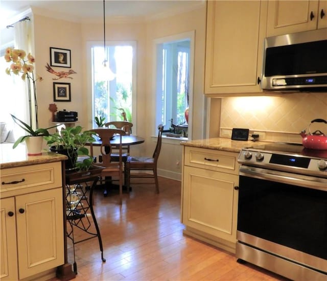 kitchen with light stone countertops, appliances with stainless steel finishes, light wood-type flooring, tasteful backsplash, and pendant lighting