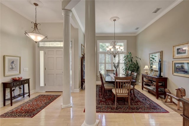 dining space with ornamental molding, hardwood / wood-style flooring, ornate columns, and a notable chandelier