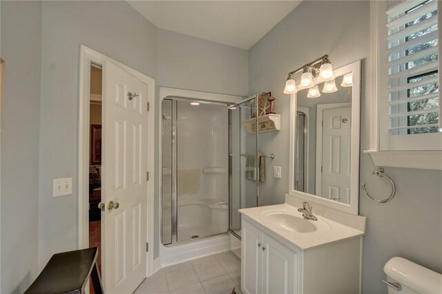 bathroom featuring tile patterned flooring, vanity, toilet, and a shower with door