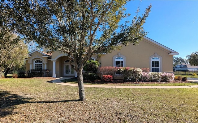 view of front of property with french doors, stucco siding, and a front lawn