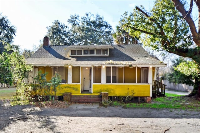 bungalow-style home featuring a porch, a shingled roof, and a chimney