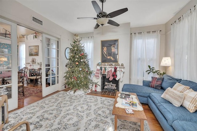 living room featuring ceiling fan, wood-type flooring, and a tile fireplace