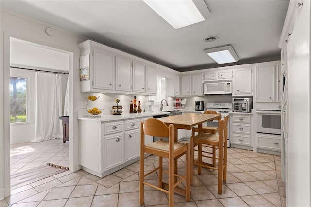 kitchen with white cabinets, light tile patterned floors, white appliances, and sink