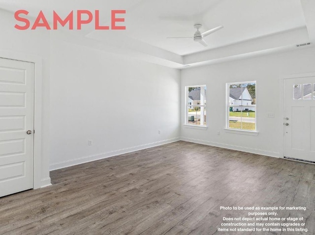 interior space with ceiling fan, wood-type flooring, and a tray ceiling