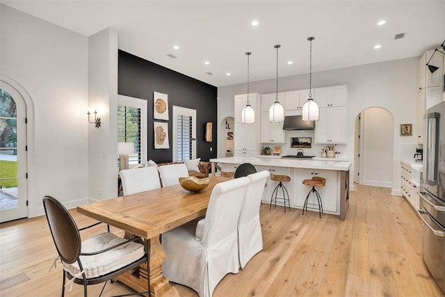 kitchen with pendant lighting, light hardwood / wood-style flooring, ceiling fan, white cabinets, and stainless steel appliances