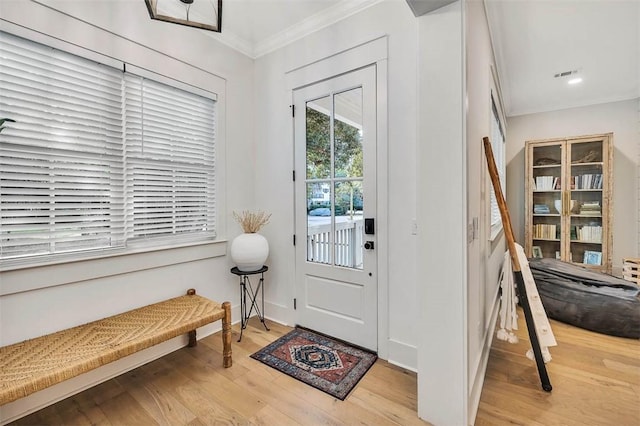 doorway to outside with a notable chandelier, light hardwood / wood-style floors, and ornamental molding