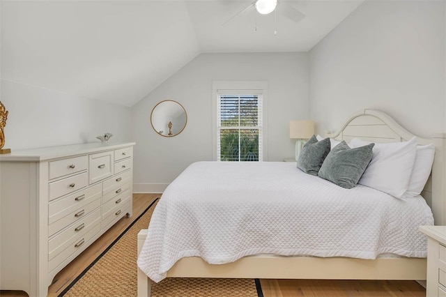 bedroom featuring light hardwood / wood-style floors, vaulted ceiling, and ceiling fan