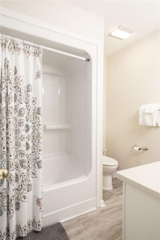 200 Salt Air Dr Unit 139, Saint Simons Island, GA 31522 - bathroom featuring toilet, wood finished floors, vanity, shower / tub combo with curtain, and baseboards