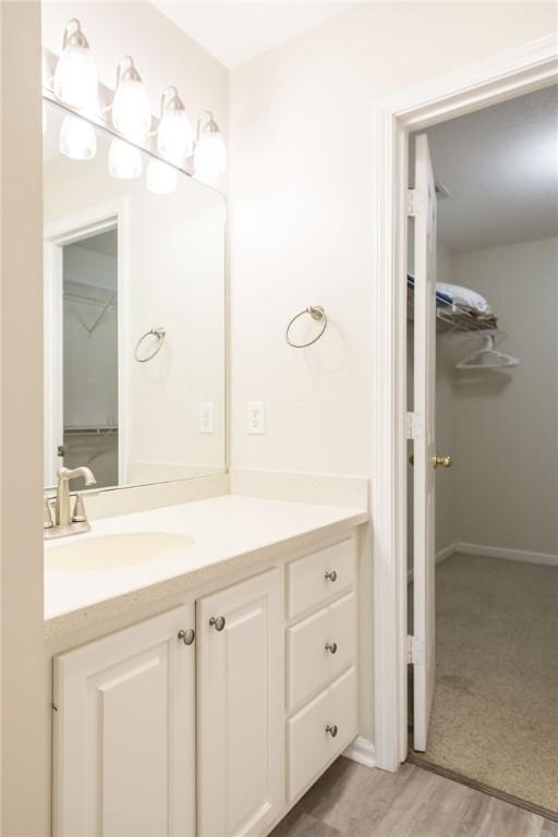 200 Salt Air Dr Unit 139, Saint Simons Island, GA 31522 - bathroom featuring vanity, a spacious closet, wood finished floors, and baseboards