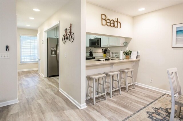 200 Salt Air Dr Unit 139, Saint Simons Island, GA 31522 - kitchen with stainless steel refrigerator with ice dispenser, a breakfast bar, light wood-style floors, baseboards, and light countertops