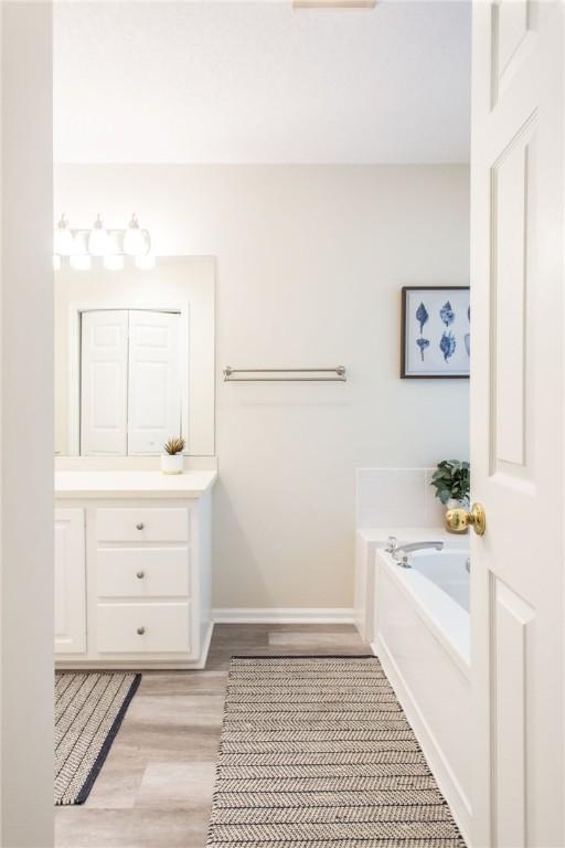 200 Salt Air Dr Unit 139, Saint Simons Island, GA 31522 - full bathroom with vanity, a garden tub, wood finished floors, and baseboards