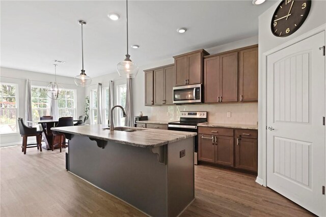 64 Wellington Cir, Brunswick, GA 31525 - kitchen with stainless steel appliances, a kitchen bar, wood finished floors, a kitchen island with sink, and pendant lighting