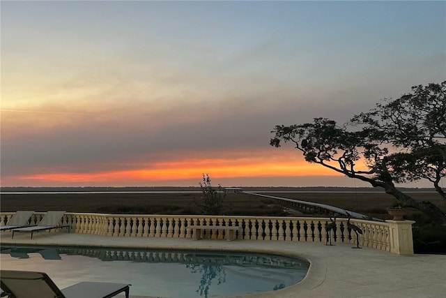 pool at dusk with a patio area