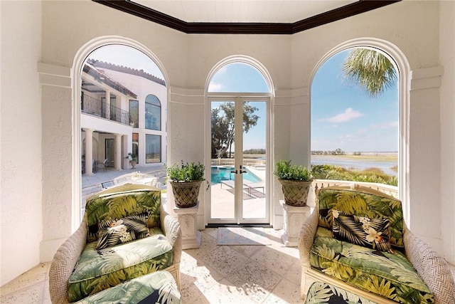 entryway with crown molding, a water view, and french doors