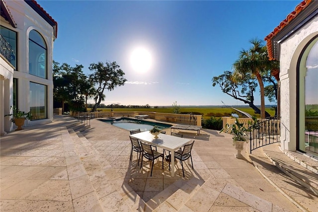 patio terrace at dusk with a fenced in pool