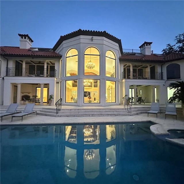 back of property featuring a balcony, a patio, and solar panels