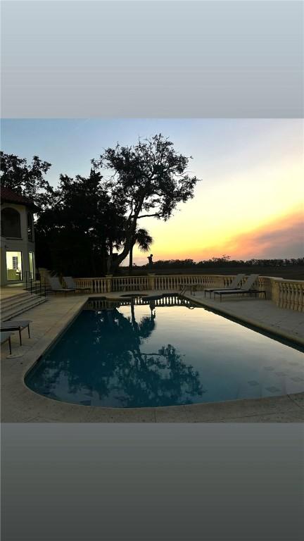 pool at dusk featuring a patio area