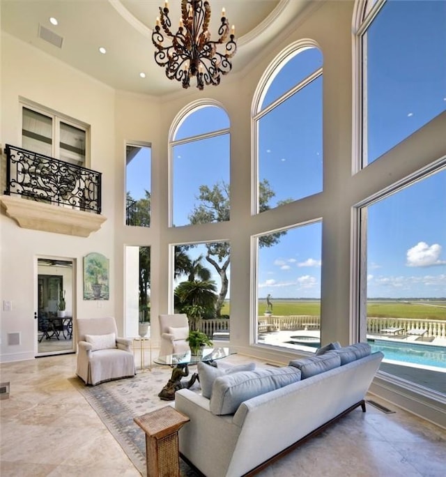 living room with an inviting chandelier, a towering ceiling, and crown molding