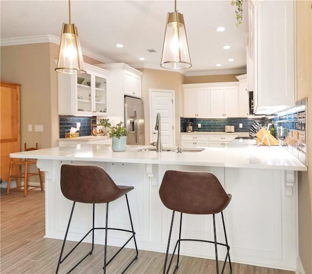 kitchen featuring a breakfast bar area, white cabinetry, stainless steel refrigerator with ice dispenser, and a sink