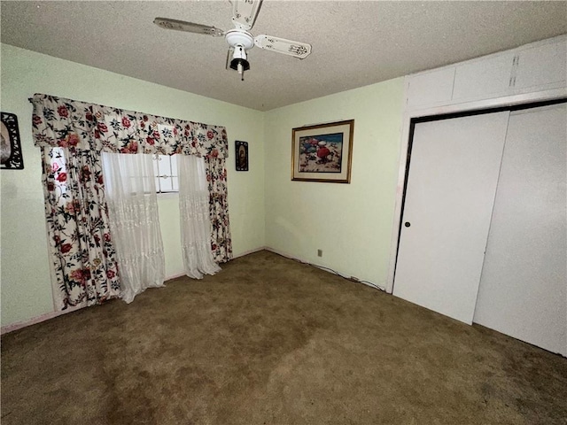 unfurnished bedroom featuring dark colored carpet, ceiling fan, a textured ceiling, and a closet