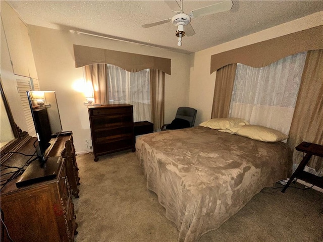 carpeted bedroom featuring ceiling fan and a textured ceiling