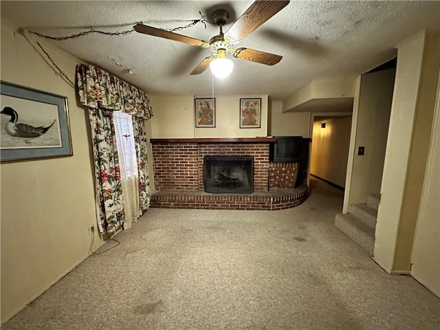 unfurnished living room with ceiling fan, a fireplace, a textured ceiling, and carpet flooring