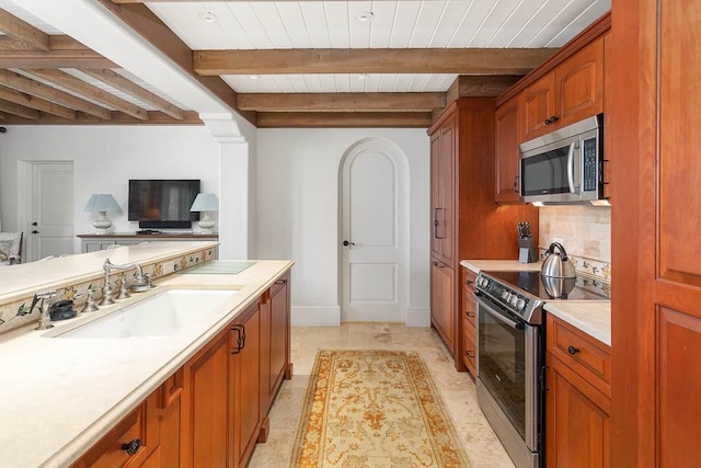 kitchen featuring sink, stainless steel appliances, beamed ceiling, decorative backsplash, and light tile patterned floors