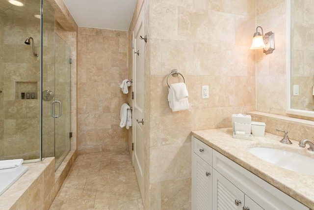 bathroom featuring a shower with door, vanity, and tile walls