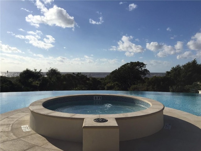 view of swimming pool with an in ground hot tub and a water view