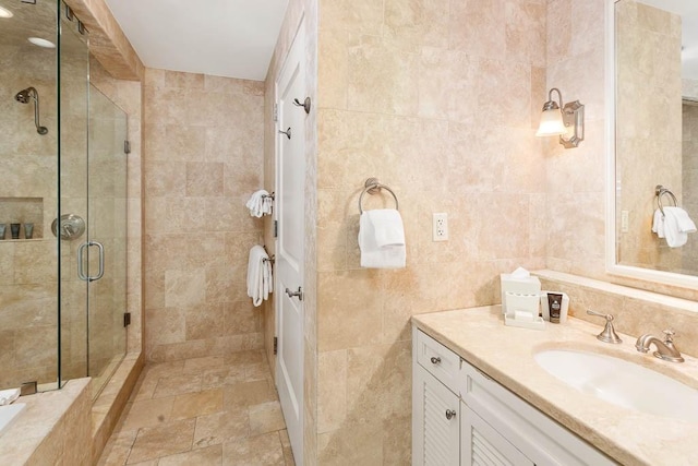 bathroom featuring vanity, a shower with shower door, and tile walls