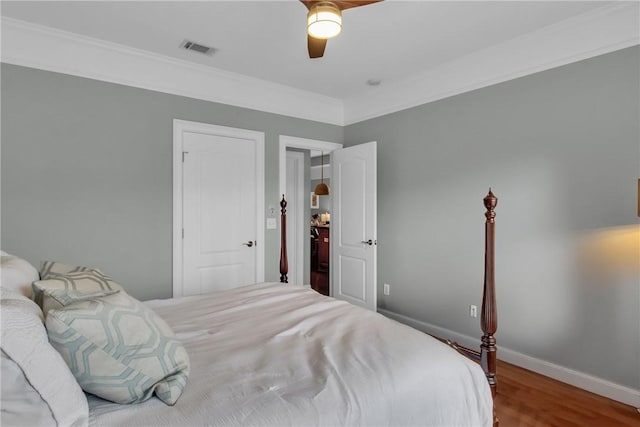 bedroom featuring baseboards, visible vents, ceiling fan, ornamental molding, and wood finished floors