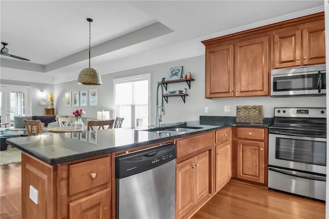 kitchen with appliances with stainless steel finishes, open floor plan, a peninsula, hanging light fixtures, and french doors