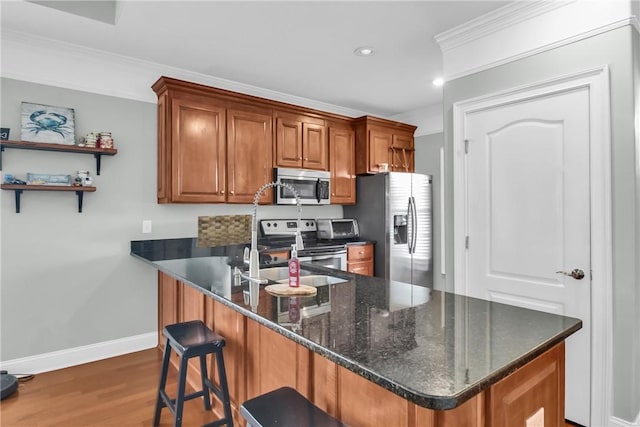 kitchen featuring brown cabinetry, appliances with stainless steel finishes, ornamental molding, a peninsula, and a sink