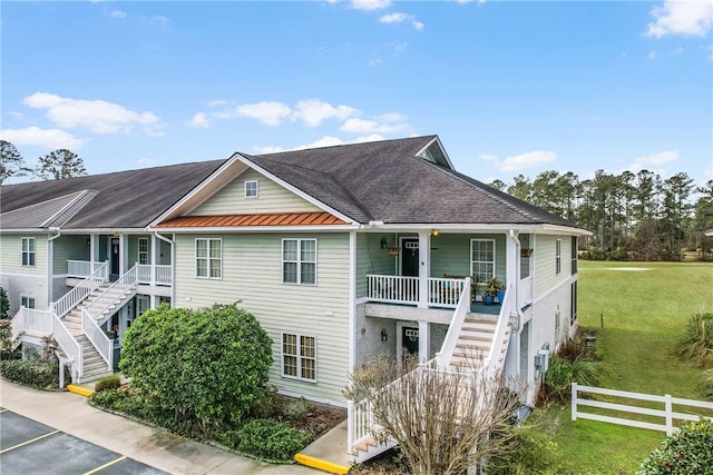 view of front of house featuring stairway, a standing seam roof, metal roof, fence, and a front lawn