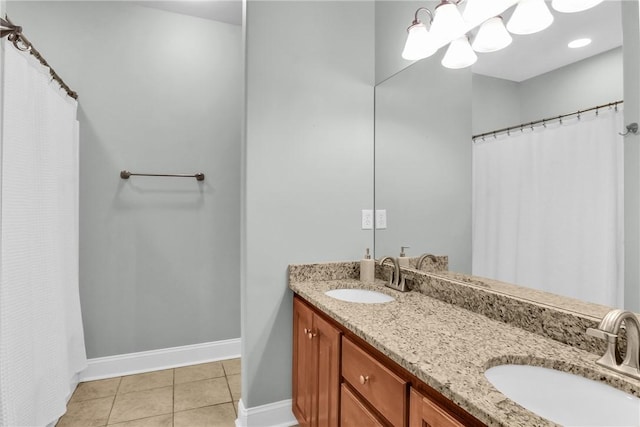 full bath with baseboards, double vanity, a sink, and tile patterned floors