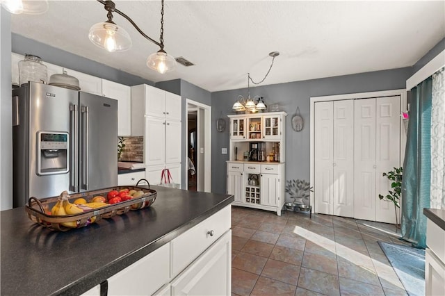 kitchen featuring backsplash, an inviting chandelier, white cabinets, high quality fridge, and decorative light fixtures