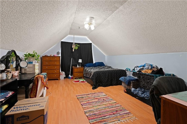 bedroom with hardwood / wood-style floors, lofted ceiling, and a textured ceiling