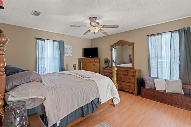 bedroom with ceiling fan, wood-type flooring, and a textured ceiling