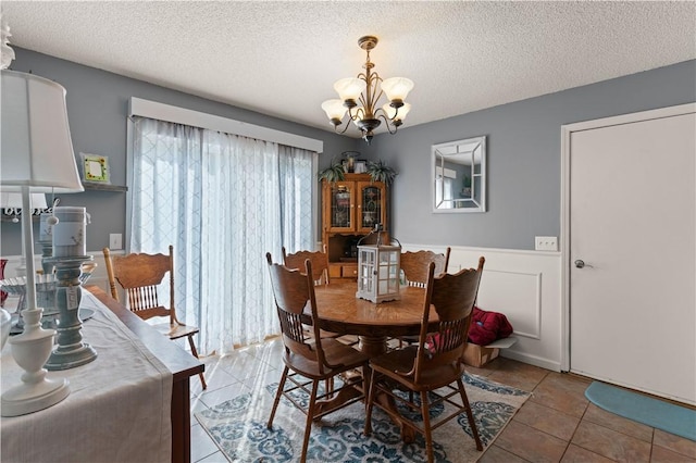 tiled dining area with a textured ceiling and an inviting chandelier