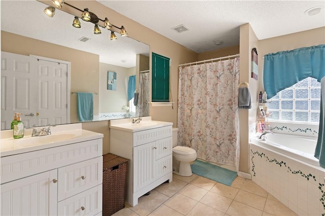 bathroom featuring tile patterned flooring, vanity, a textured ceiling, and tiled bath