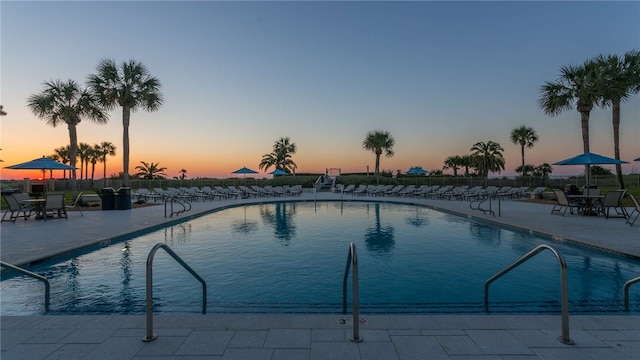 pool at dusk featuring a patio