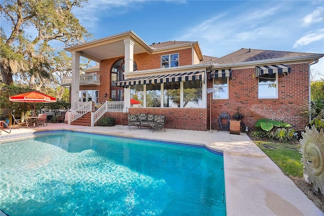 rear view of house featuring a balcony and a patio