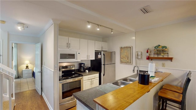 kitchen featuring sink, white cabinetry, a kitchen bar, kitchen peninsula, and stainless steel appliances